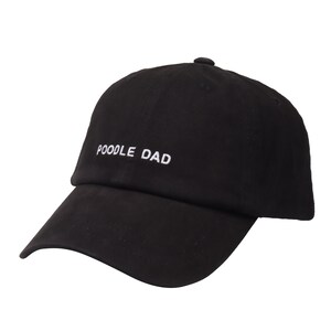 Pu&ograve; includere: Un cappello da baseball nero con il testo "POODLE DAD" ricamato in bianco sul davanti.