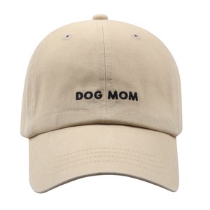 May include: A beige baseball cap with black embroidery that reads "DOG MOM".