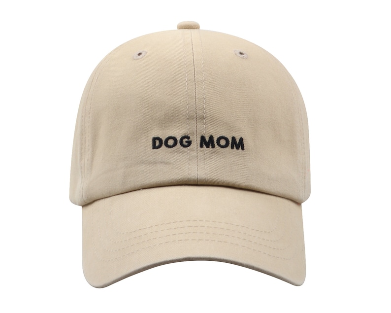 May include: A beige baseball cap with black embroidery that reads "DOG MOM".