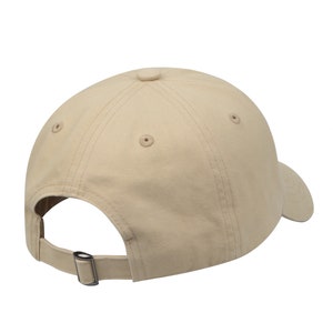 May include: A beige baseball cap with a curved brim and an adjustable strap. The cap is made of a soft, cotton fabric.