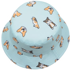 May include: A light blue bucket hat with a pattern of cartoon corgis in various poses. The corgis are brown, black, and white.