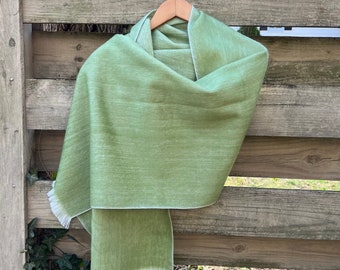 May include: A soft, green scarf with a white fringe. The scarf is made of a lightweight material and has a subtle sheen.
