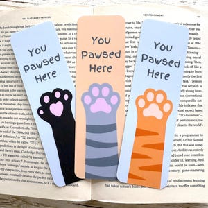 Lesezeichen mit Katzenpfote „Hier hast du deine Pfote hingelegt“. Beidseitig bedruckt, laminiert, mit oder ohne Quaste. Das perfekte Geschenk für Katzen- und Bücherliebhaber. Einzeln oder im 3er-Set erhältlich.