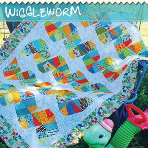 May include: A colorful quilt kit with the text "Wiggleworm" and "X-Blocks Basix" on the packaging. The quilt features a patchwork design with various patterned fabrics in blue, green, orange, and red. The kit is designed for 2.5" strips.