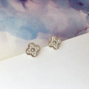 May include: A pair of silver earrings with a four-leaf clover design. Each clover is adorned with small, clear crystals.