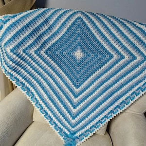 May include: A blue and white crocheted baby blanket with a diamond pattern and a white satin ribbon border.