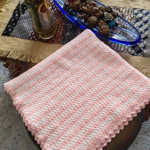 May include: A pink and white striped crocheted baby blanket with a scalloped edge.