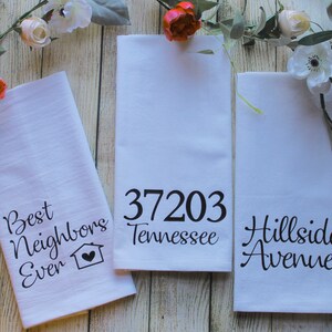 May include: Three white kitchen towels with black text. One towel reads "Best Neighbors Ever" with a house and heart icon. Another displays "37203 Tennessee". The third towel says "Hillside Avenue".