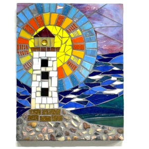 May include: A mosaic artwork depicting a lighthouse with a yellow and orange sunburst design. The lighthouse is white with black windows, set against a blue ocean and a purple and pink sky. The base of the lighthouse is made of stones. The number "#2" is at the bottom.