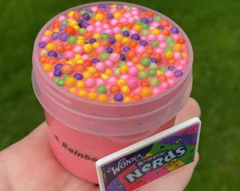 May include: Pink slime with colorful sprinkles in a clear plastic container with a Wonka Rainbow Nerds label.