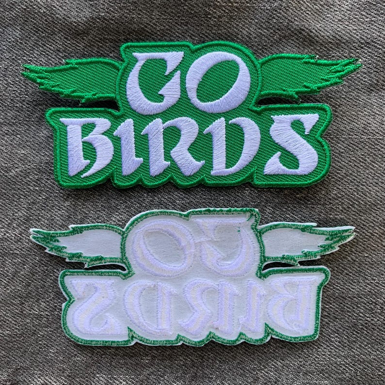 May include: Two green and white embroidered patches with the text "GO BIRDS" in a stylized font. The top patch has green wings and the bottom patch has white wings.