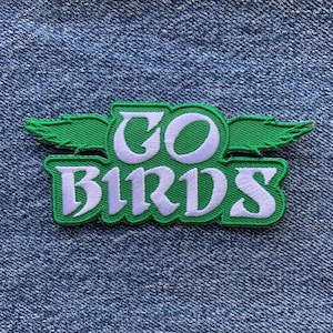May include: Green and white embroidered patch with the words "GO BIRDS" and a stylised bird wing design.