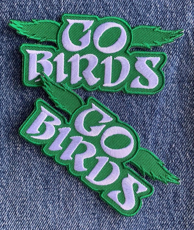 May include: Two green and white embroidered patches with the text "GO BIRDS" in a white cursive font. The patches have a green bird wing design.
