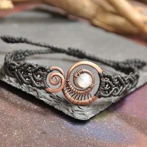 Può includere: Un braccialetto intrecciato nero con un design a spirale in filo di rame e una perla di pietra di luna bianca.
