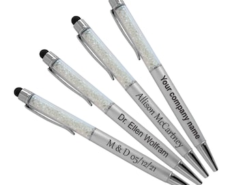 May include: Four silver pens with clear crystal accents and black stylus tips. Each pen is engraved with a different name and date. The pens are arranged in a stack, with the top pen showing the text "Your company name".
