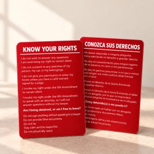 Pode incluir: Dois cartões retangulares vermelhos com texto branco. O cartão da esquerda intitula-se KNOW YOUR RIGHTS e lista declarações legais sobre silêncio e buscas. O cartão da direita intitula-se CONOZCA SUS DERECHOS e apresenta as mesmas informações em espanhol.