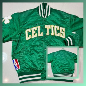 Może przedstawiać: Zielona satynowa kurtka z napisem "CELTICS" w złotych literach. Kurtka ma biało-zielone paski na mankietach i kołnierzu oraz naszywkę z koniczyną. Na przodzie widoczna jest naszywka z logo NBA. Widoczny jest również mniejszy obraz tyłu kurtki.
