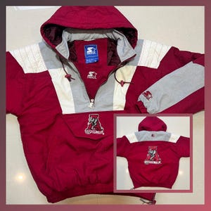 May include: Crimson and gray Starter pullover jacket with a hood. The jacket features a half-zip closure, a front pocket, and the "Crimson Tide" logo. The sleeves are gray with a red logo. The jacket has a Starter logo on the chest.