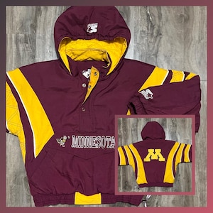 May include: A maroon and gold vintage Starter jacket with a Minnesota logo and a gold and white striped design. The jacket has a hood and a snap button closure.