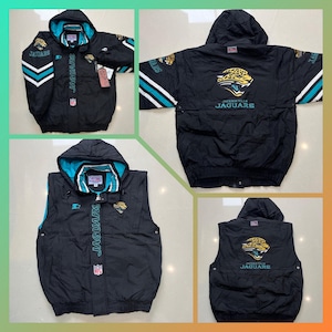 May include: Black Jacksonville Jaguars jacket and vest set. The jacket has a teal and white stripe design on the sleeves and the team logo on the chest. The vest has a teal and white stripe design on the sides and the team logo on the chest.