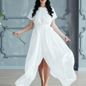 Linen wedding dress close-up, model holding flower stem
