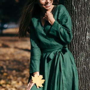 Green linen wrap dress, smiling model holding autumn leaf