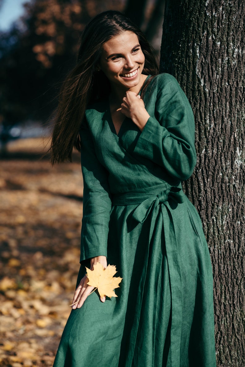 Green linen wrap dress, smiling model holding autumn leaf