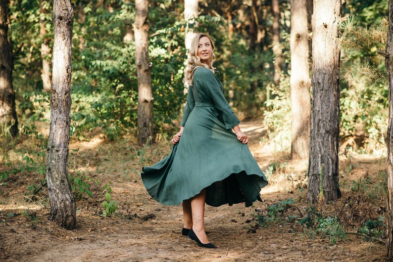 Green long sleeve linen wrap dress twirling in forest, skirt in motion