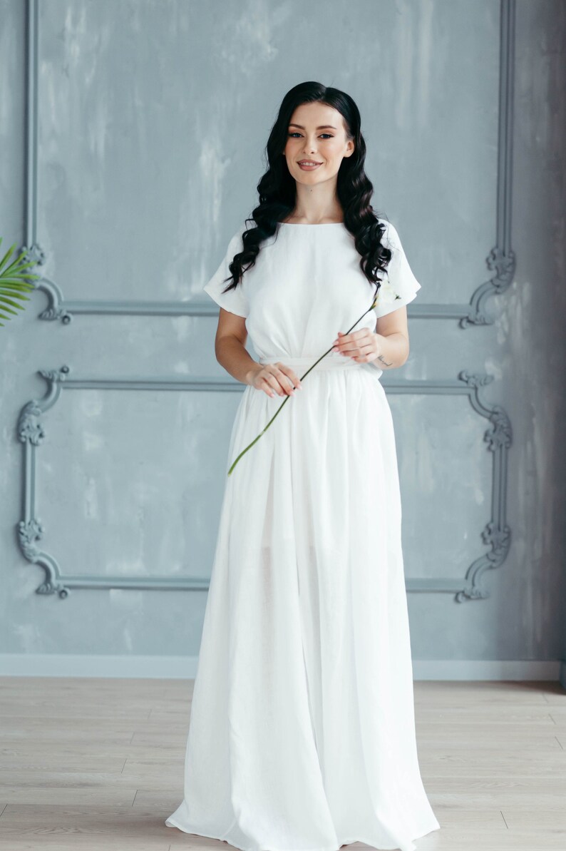 Linen wedding dress with sleeves, styled against grey backdrop