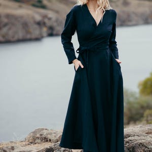 Navy linen wrap dress worn on rocky coastal landscape, full skirt