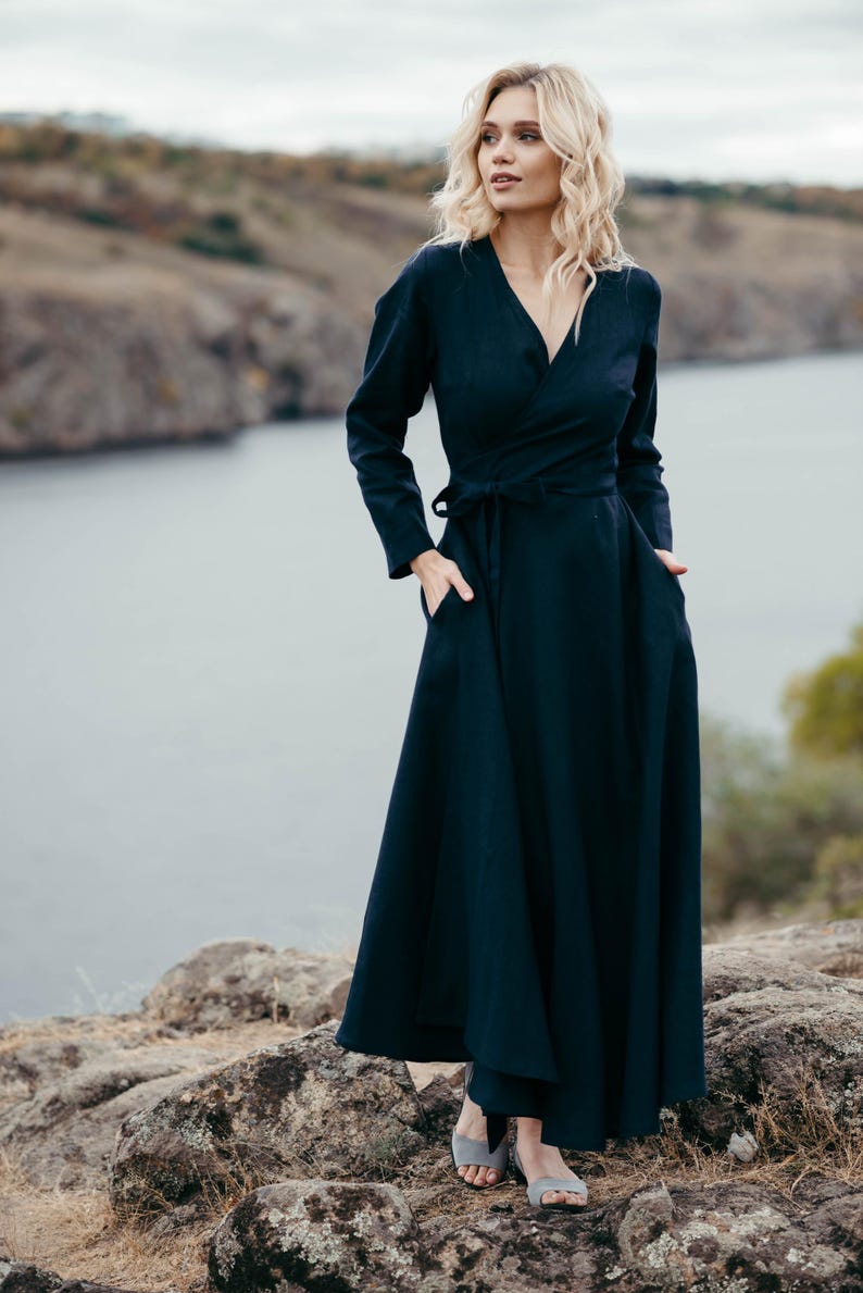 Navy linen wrap dress worn on rocky coastal landscape, full skirt
