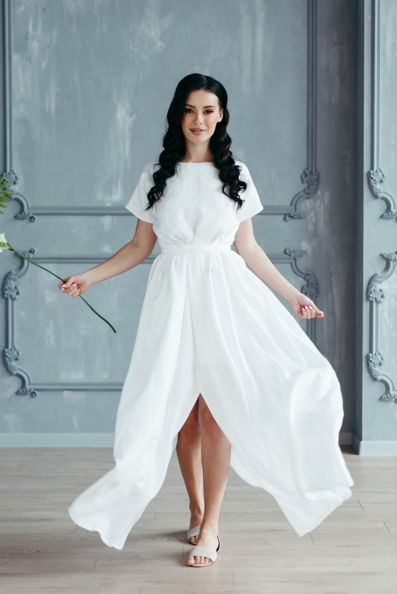 Linen wedding dress close-up, model holding flower stem