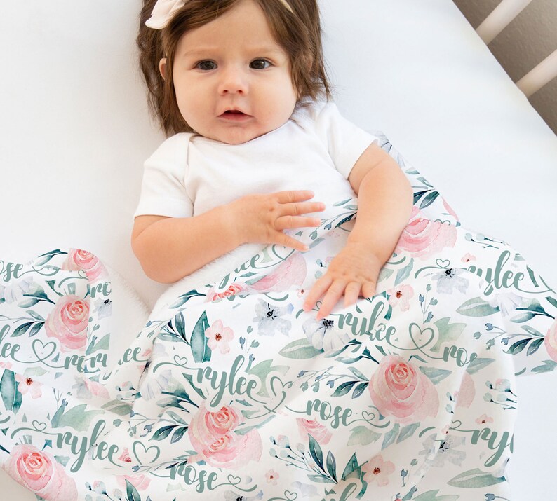 May include: A white baby blanket featuring a floral design and the name "Rylee Rose" written in cursive. The blanket is made from soft, breathable fabric, ideal for snuggling.