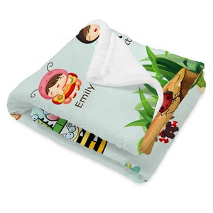 May include: A light blue fleece blanket with a white sherpa lining. The blanket features a whimsical design with a girl dressed as a ladybug, a bee, a ladybug, and a butterfly. The text "Emily" is printed on the blanket.