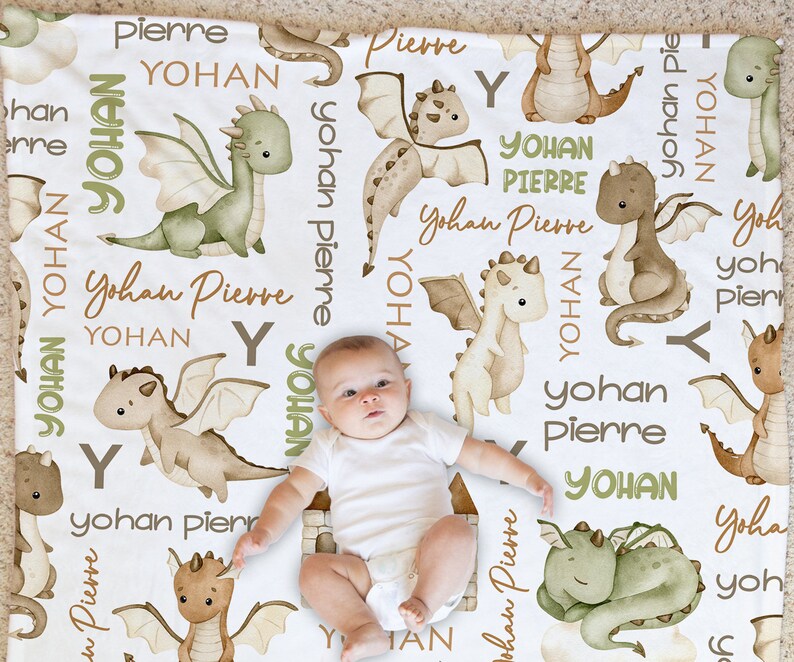 May include: A white baby blanket with a repeating pattern of green and brown dragons and the names "Yohan" and "Pierre".
