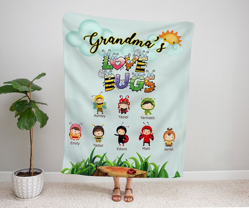 May include: A light blue and green blanket with the text "Grandma's Love Bugs" in black. The blanket features a cartoon illustration of a sun, a heart, and several bugs with names written below them. The names are: Emily, Yadiel, Edwin, Matt, and Jariel.
