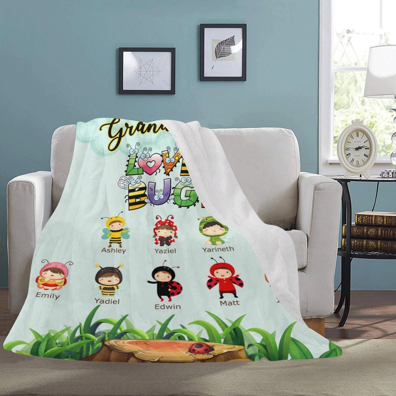 May include: A personalized fleece blanket with a light blue background and a cartoon illustration of a ladybug with the text "Grandma's Love Bugs". The blanket features a variety of cartoon bugs with names such as Ashley, Yaziel, Yarineth, Emily, Yadiel, Edwin, and Matt.