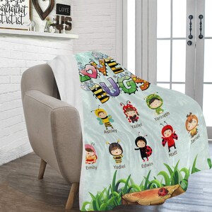 May include: A light blue fleece blanket with the words "Love Bugs" in colorful letters.  The blanket features a variety of cartoon bugs with names like Ashley, Yaziel, Yarineth, and Matt.