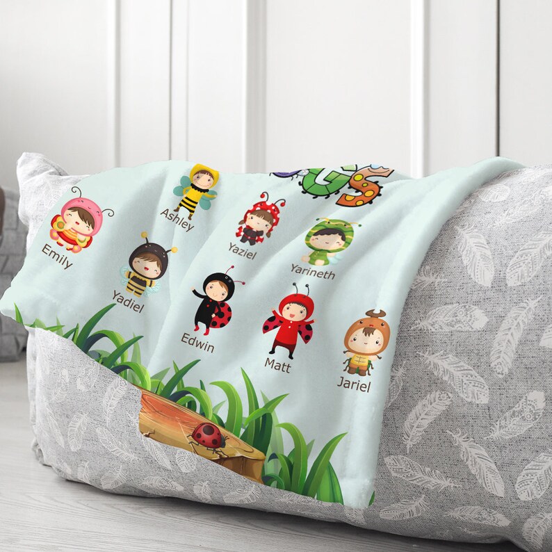 May include: A light blue baby blanket with a green grass and tree design. The blanket features a variety of colorful cartoon bugs with names written below each bug. The names include: Emily, Ashley, Yaziel, Yarineth, Yadiel, Edwin, Matt, and Jariel.
