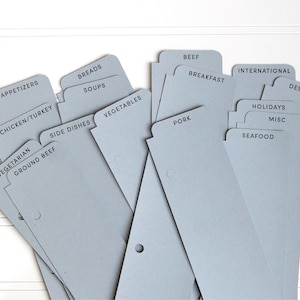 May include: A set of light gray recipe book dividers with black printed text labels including Appetizers, Breads, Soups, Chicken/Turkey, Side Dishes, Vegetables, Beef, Breakfast, Pork, International, Desserts, Holidays, Misc, Seafood, Vegetarian, and Ground Beef.