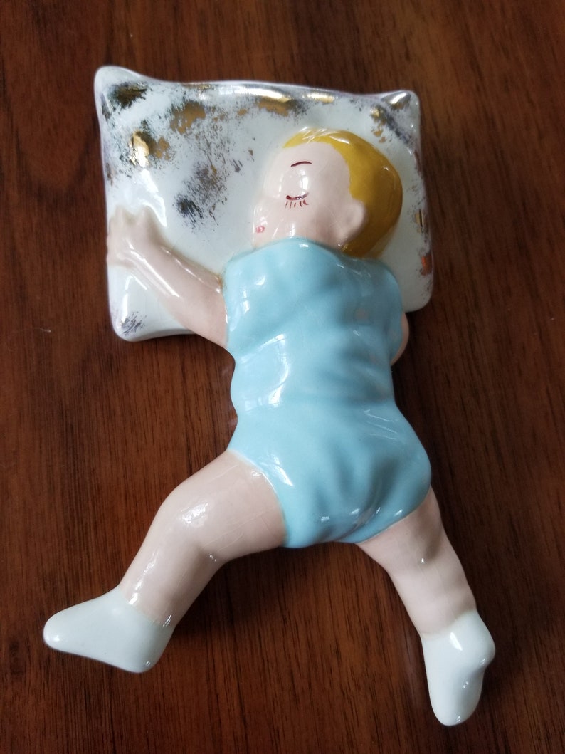 1950s ceramic baby boy sleeping on pillow with blue onesie and image 0