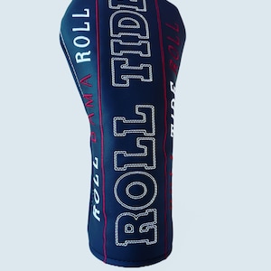 May include: Black golf club head cover with white stitching and red accents. The cover has the text "Rollin' D'ma Roll" and "Rollin' Tide" on it.