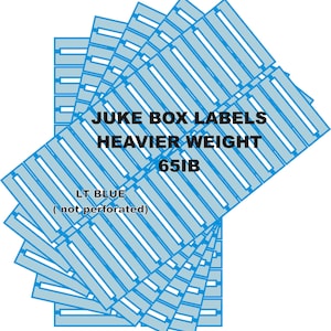 May include: A stack of light blue rectangular jukebox labels with white center strips. The text reads JUKE BOX LABELS HEAVIER WEIGHT 65LB LT BLUE ( not perforated ). The labels are arranged in a fanned pattern, showing multiple identical sheets.