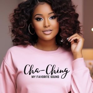 Puede incluir: Sudadera rosa con el texto "Cha-Ching My Favorite Sound" en letras cursivas negras.