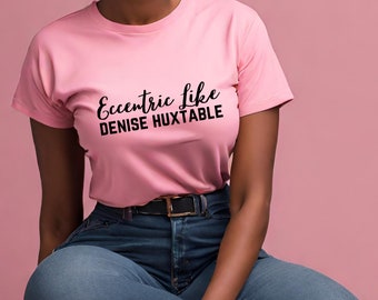 May include: A pink t-shirt with black text that reads "Eccentric Like Denise Huxtable".