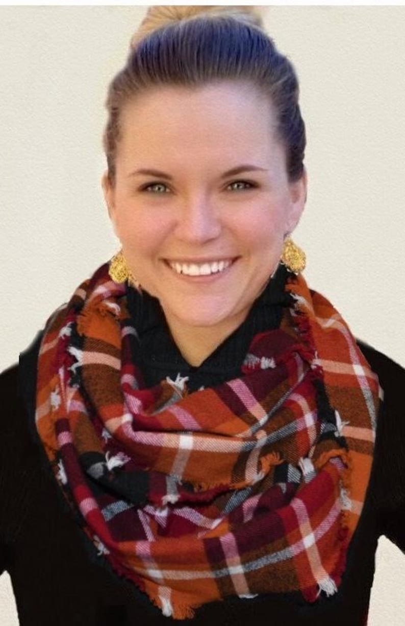 May include: A red, orange, black, and white plaid infinity scarf with frayed edges.