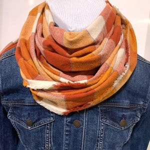 May include: A warm, orange and white plaid infinity scarf. The scarf is made of a soft, fuzzy material and is perfect for keeping warm in the winter.