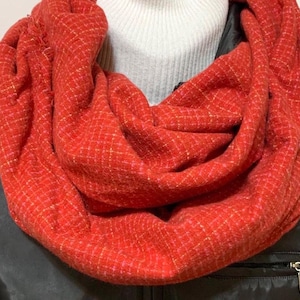 May include: A red infinity scarf with a checkered pattern. The scarf is made of a soft, fuzzy material.
