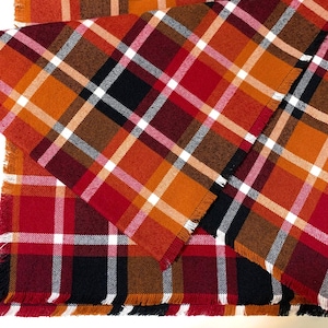 May include: Two plaid table runners in red, orange, brown, and white with frayed edges.
