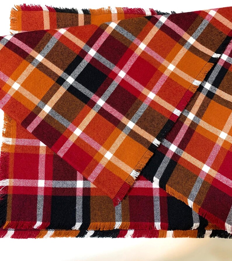 May include: Two plaid table runners in red, orange, brown, and white with frayed edges.